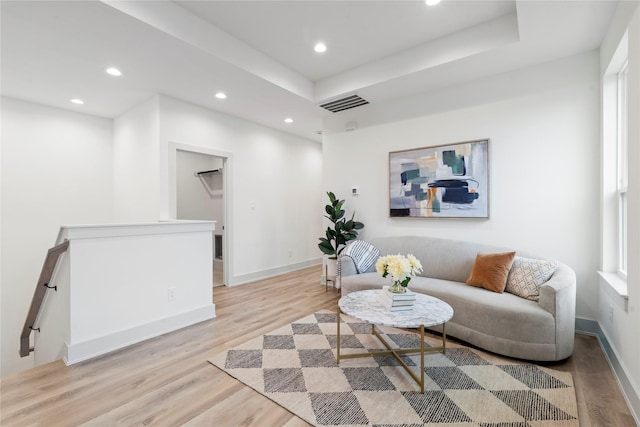 living room with a tray ceiling and light hardwood / wood-style floors