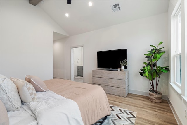 bedroom featuring ceiling fan, connected bathroom, high vaulted ceiling, and light wood-type flooring