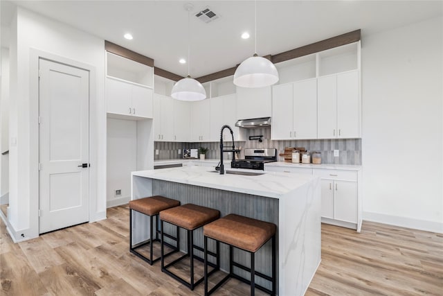 kitchen with a kitchen island with sink, hanging light fixtures, and white cabinets