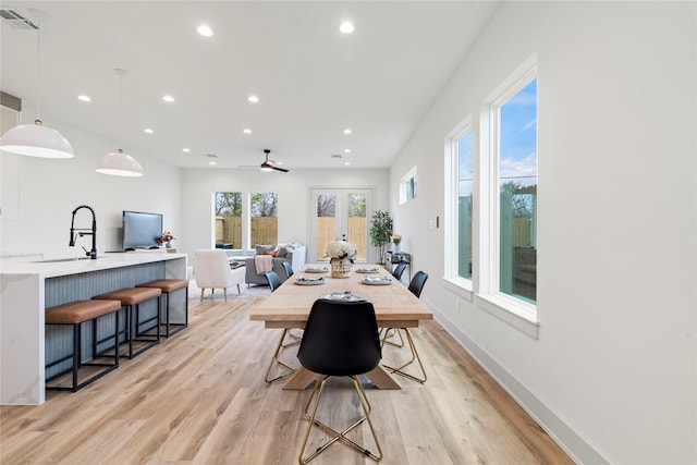 dining room with french doors, sink, and light hardwood / wood-style flooring