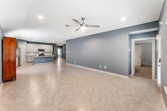 unfurnished living room with sink, ceiling fan, and light tile patterned flooring