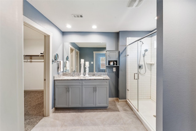 bathroom featuring tile patterned flooring, vanity, and a shower with shower door