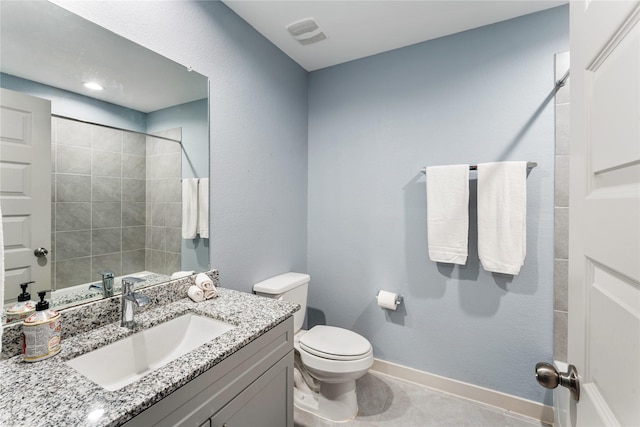 bathroom featuring vanity, tile patterned flooring, toilet, and tiled shower