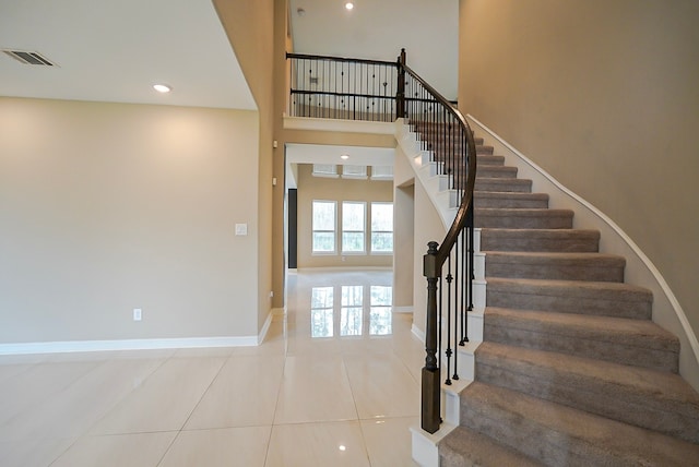 staircase with tile patterned floors and a high ceiling