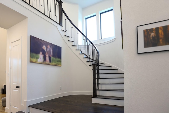 stairway featuring a high ceiling and hardwood / wood-style floors