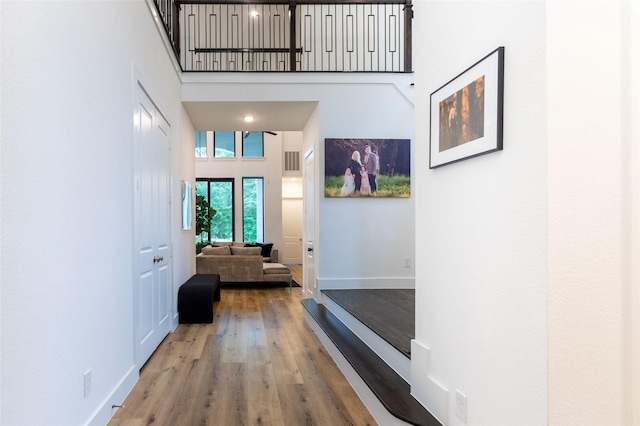 corridor with hardwood / wood-style floors and a high ceiling