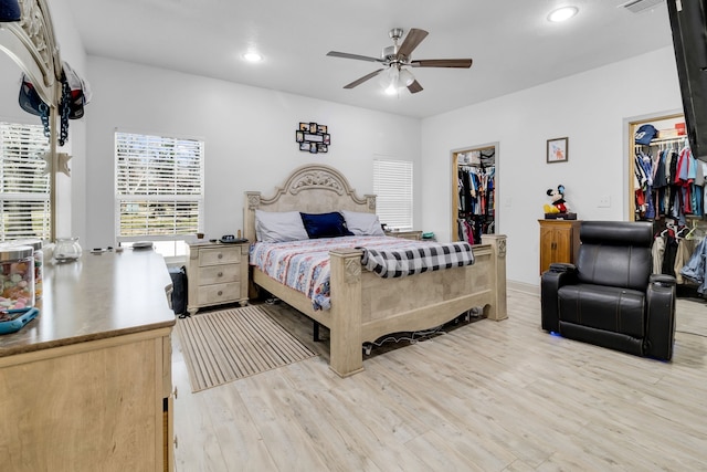 bedroom featuring ceiling fan, a spacious closet, and light wood-type flooring