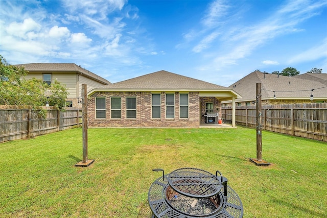 back of house with a patio area, a fire pit, and a lawn