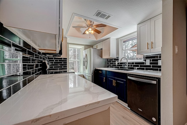 kitchen featuring dishwasher, light stone countertops, sink, and white cabinets