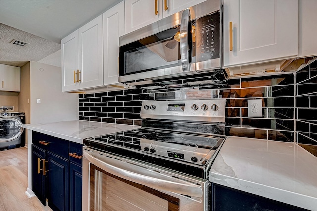 kitchen featuring appliances with stainless steel finishes, white cabinetry, light stone countertops, blue cabinets, and washer / dryer