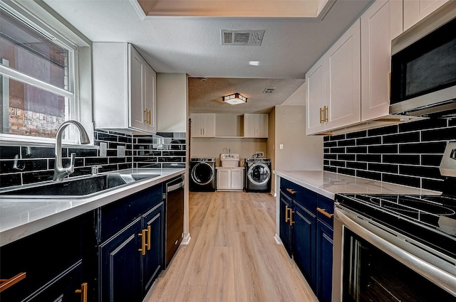 kitchen with white cabinetry, independent washer and dryer, stainless steel appliances, and sink