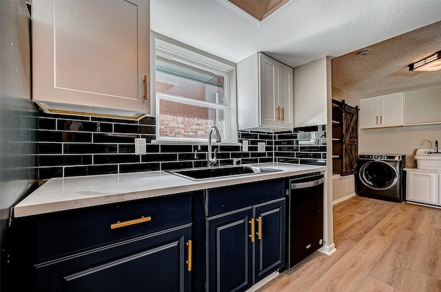 kitchen with sink, white cabinetry, black dishwasher, washer / clothes dryer, and a barn door