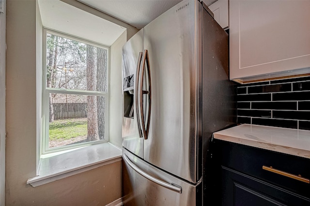 kitchen featuring backsplash, stainless steel fridge, and white cabinets