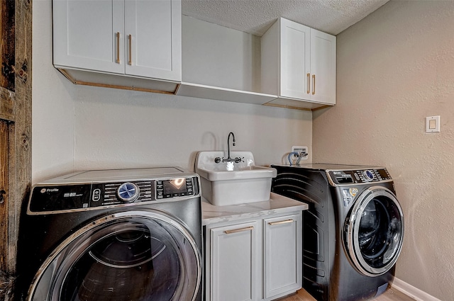 laundry area with washer and dryer, sink, cabinets, and a textured ceiling