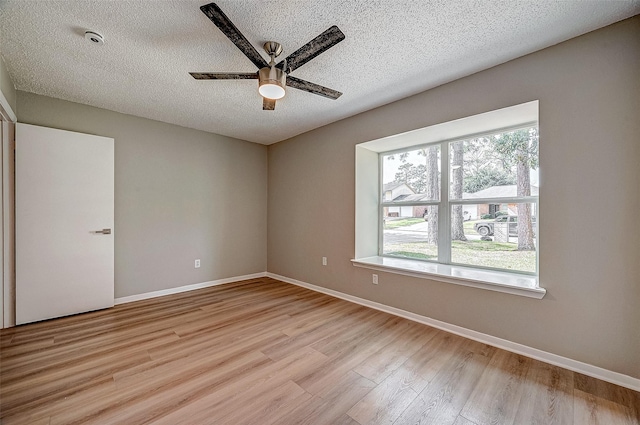 empty room featuring light hardwood / wood-style flooring, ceiling fan, plenty of natural light, and a textured ceiling