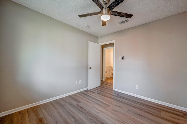 empty room with ceiling fan, light hardwood / wood-style flooring, and a textured ceiling