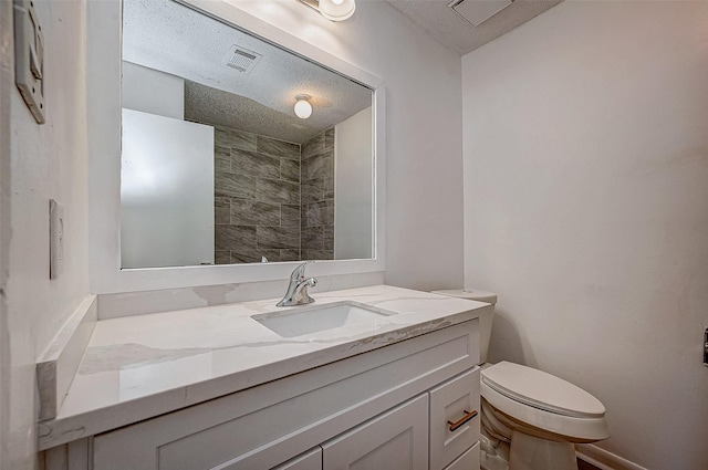 bathroom featuring vanity, a textured ceiling, and toilet