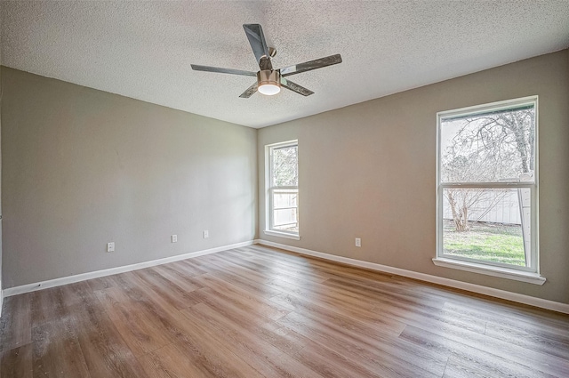 unfurnished room with ceiling fan, a textured ceiling, and light wood-type flooring