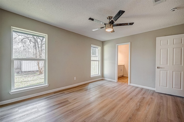 unfurnished bedroom featuring ceiling fan, connected bathroom, a textured ceiling, and light wood-type flooring