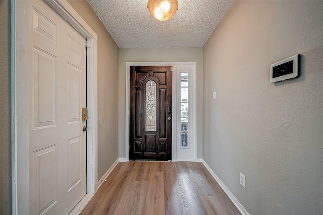 foyer entrance with light hardwood / wood-style floors and a textured ceiling