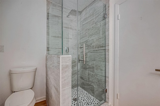 bathroom featuring a shower with shower door and toilet