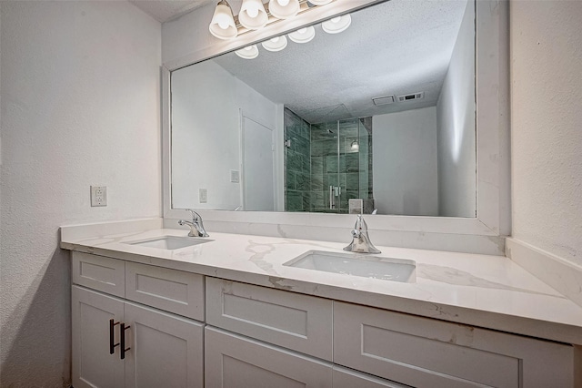 bathroom featuring vanity, a textured ceiling, and a shower with shower door