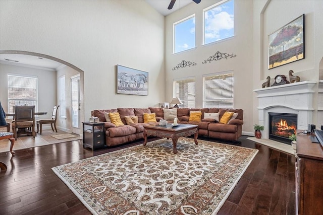 living room with crown molding, hardwood / wood-style flooring, ceiling fan, and a high ceiling