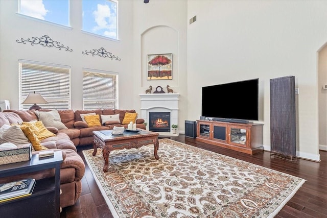 living room featuring a healthy amount of sunlight, dark hardwood / wood-style flooring, and a high ceiling