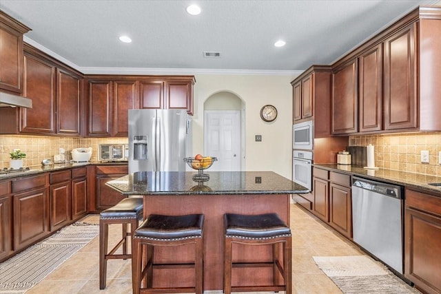 kitchen featuring stainless steel appliances, dark stone countertops, and a kitchen breakfast bar