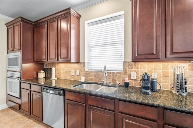 kitchen featuring backsplash, appliances with stainless steel finishes, sink, and dark stone countertops