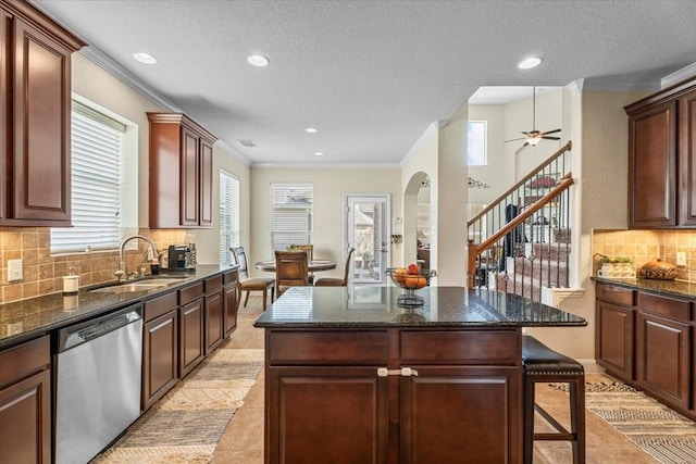 kitchen with crown molding, stainless steel dishwasher, sink, and a kitchen island