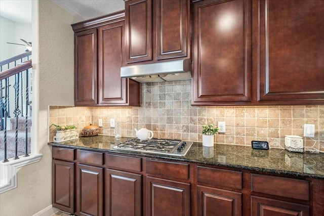 kitchen with tasteful backsplash, stainless steel gas stovetop, and dark stone countertops