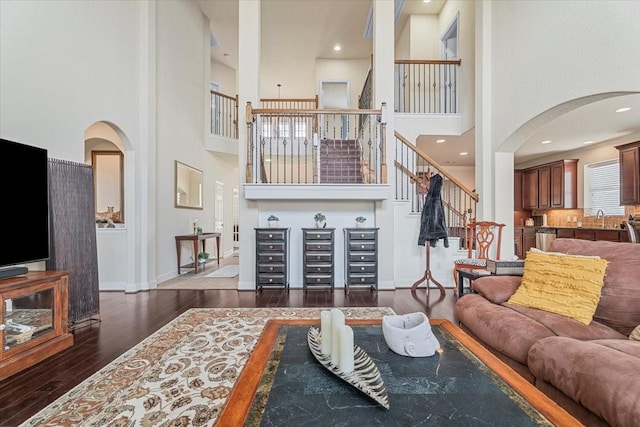 living room featuring a towering ceiling, dark hardwood / wood-style flooring, and sink