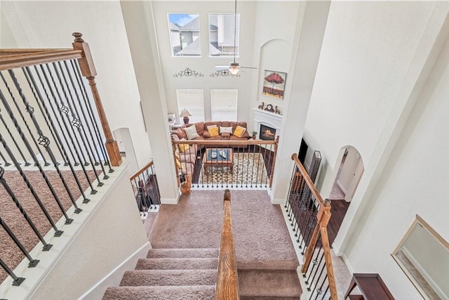 stairway with carpet floors, ceiling fan, and a high ceiling