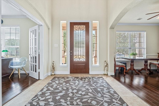 foyer entrance with crown molding, wood-type flooring, and ceiling fan