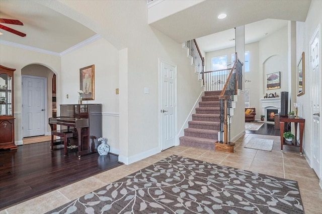 foyer with tile patterned flooring, ornamental molding, and ceiling fan