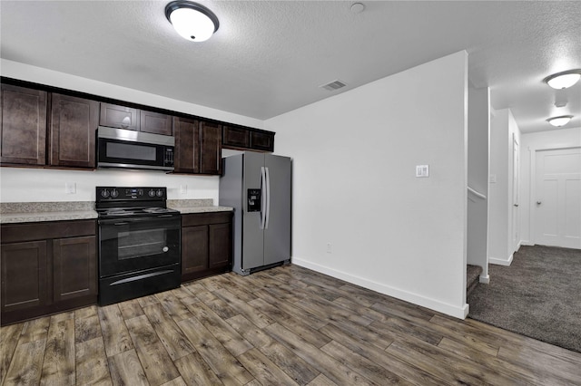 kitchen with dark brown cabinetry, hardwood / wood-style floors, stainless steel appliances, and a textured ceiling