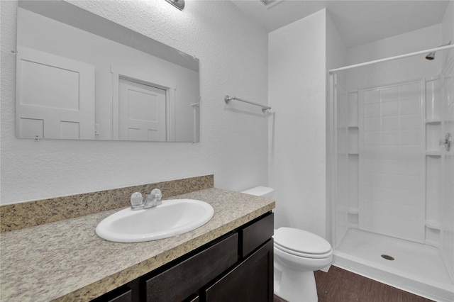 bathroom featuring vanity, hardwood / wood-style floors, a shower, and toilet