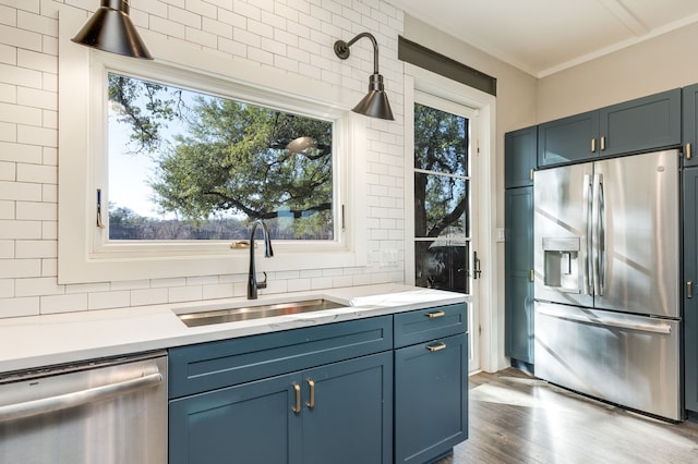 kitchen with sink, hardwood / wood-style flooring, stainless steel appliances, blue cabinets, and decorative backsplash