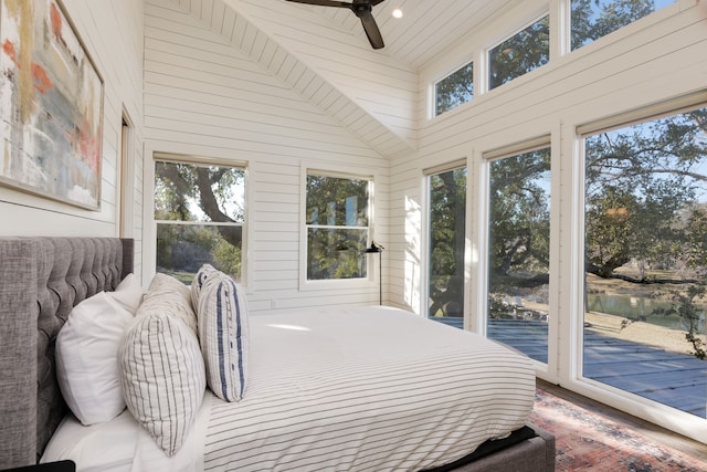 bedroom featuring multiple windows, access to exterior, wooden walls, and a water view