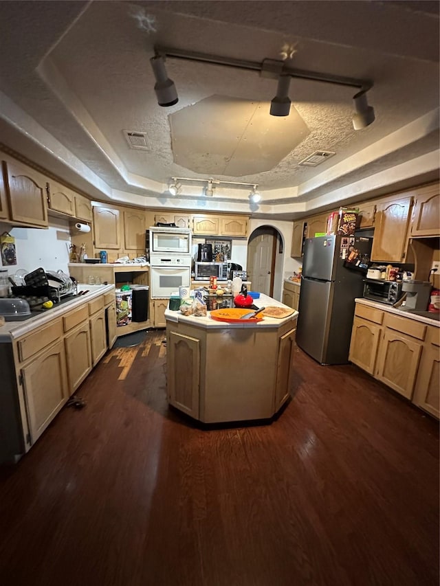 kitchen with dark wood-type flooring, built in microwave, a textured ceiling, stainless steel fridge, and a tray ceiling