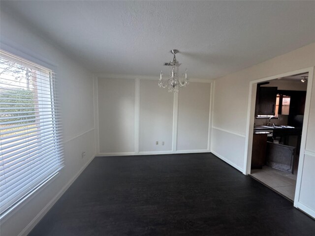 empty room featuring an inviting chandelier and dark hardwood / wood-style flooring