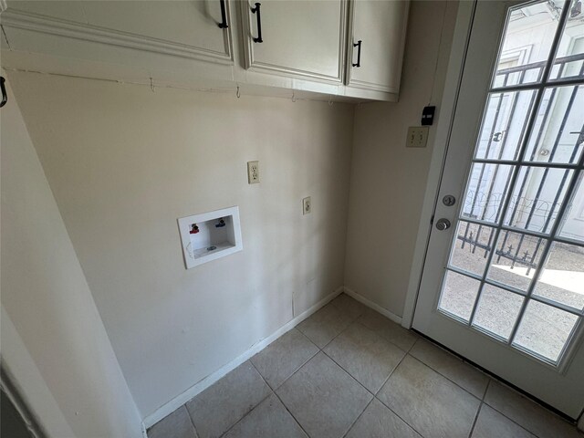 washroom with light tile patterned flooring, cabinets, and washer hookup