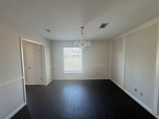 empty room featuring an inviting chandelier, a textured ceiling, and dark hardwood / wood-style flooring