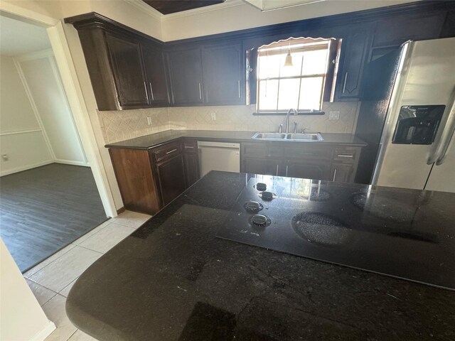 kitchen featuring tasteful backsplash, sink, white dishwasher, stainless steel refrigerator with ice dispenser, and dark brown cabinets