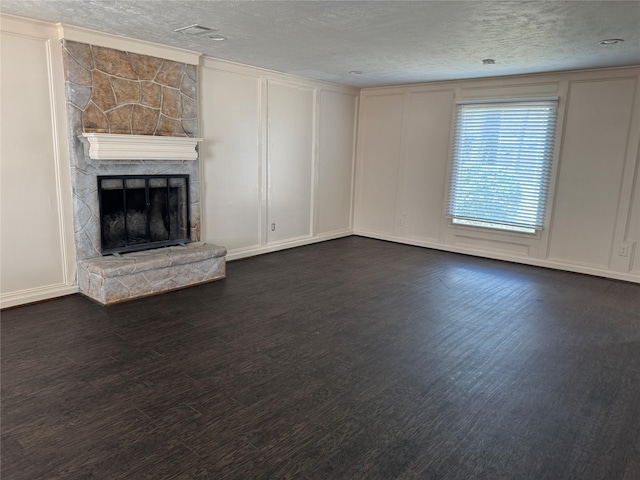 unfurnished living room featuring dark wood-type flooring, a textured ceiling, and a fireplace