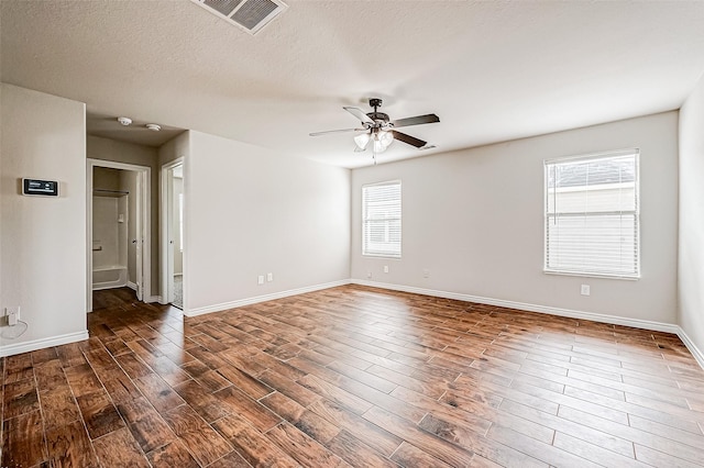 empty room featuring baseboards, ceiling fan, visible vents, and dark wood-style flooring