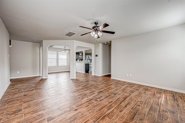 unfurnished living room with baseboards, visible vents, wood finished floors, and ceiling fan with notable chandelier