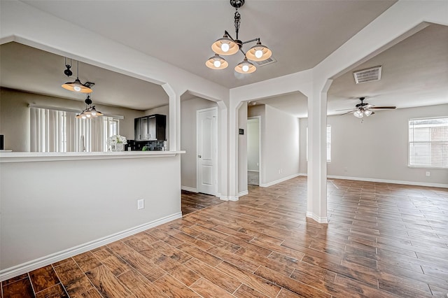 interior space with arched walkways, visible vents, a ceiling fan, wood finished floors, and baseboards