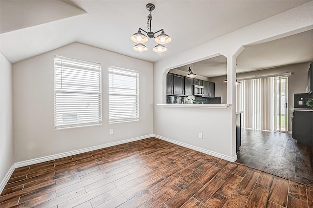 interior space featuring baseboards, vaulted ceiling, dark wood finished floors, and a notable chandelier